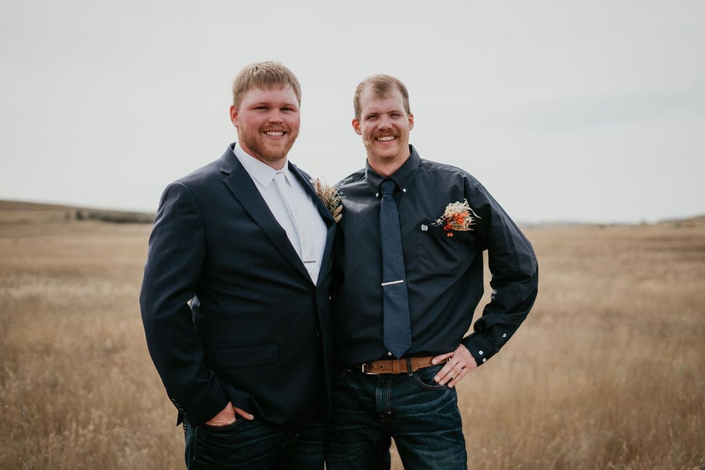 Groom and best man smiling together during Belfield North Dakota wedding photographed in the Badlands