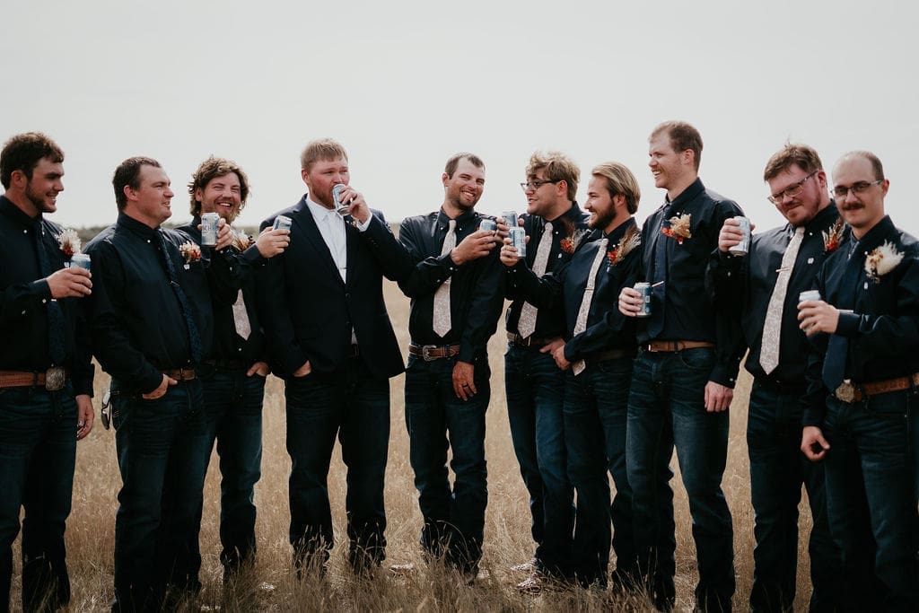 Groom laughing with groomsmen sharing drinks outdoors at Buffalo Gap wedding near Belfield North Dakota