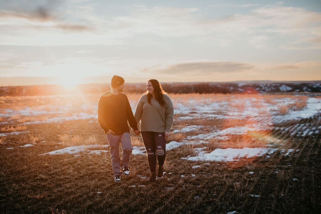 Groom holding bride’s hand at sunset in Montana