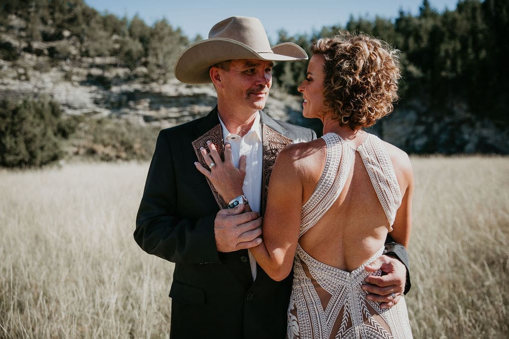 Groom adjusting boutonniere before wedding portraits on the ranch.