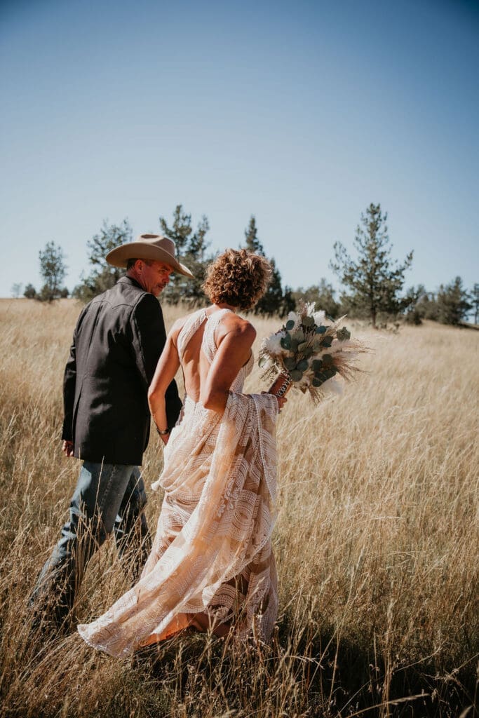 Bride’s lace wedding gown trailing across the prairie grass.