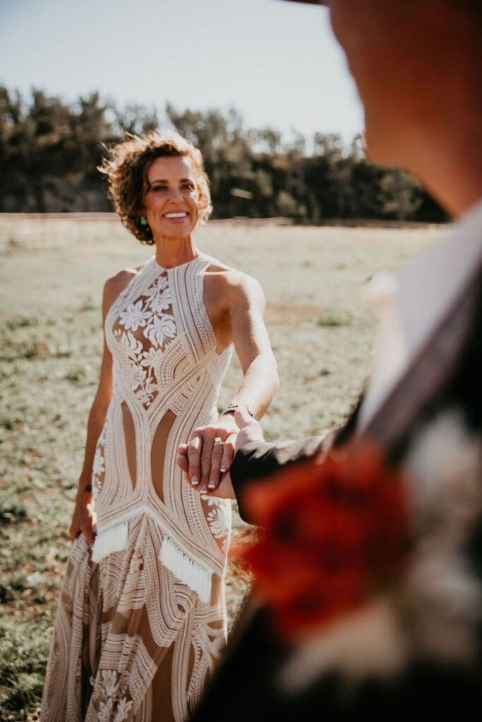 Bride looking back over shoulder with lace gown flowing behind her.