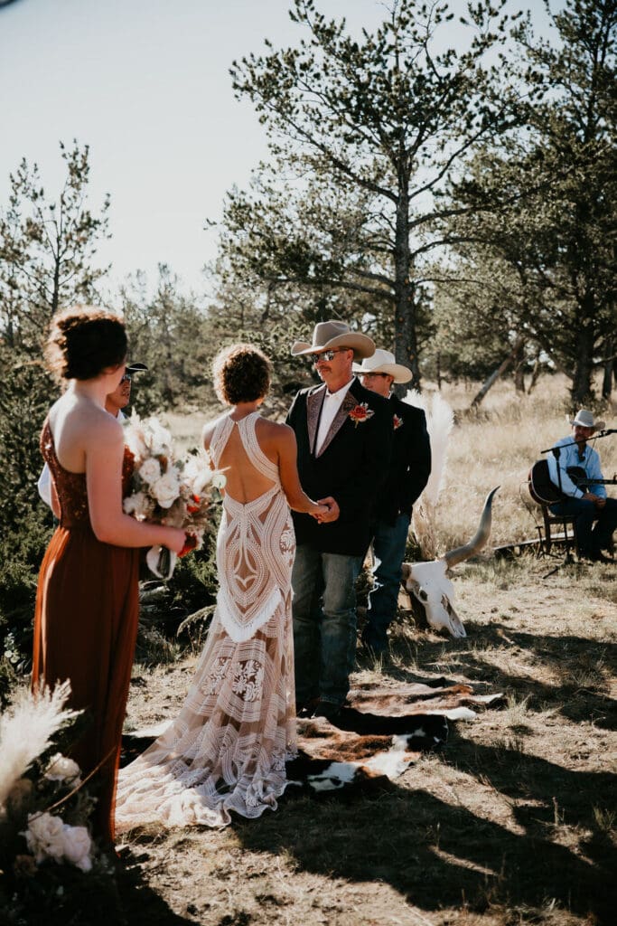 Couple smiling at each other while walking through golden pasture.