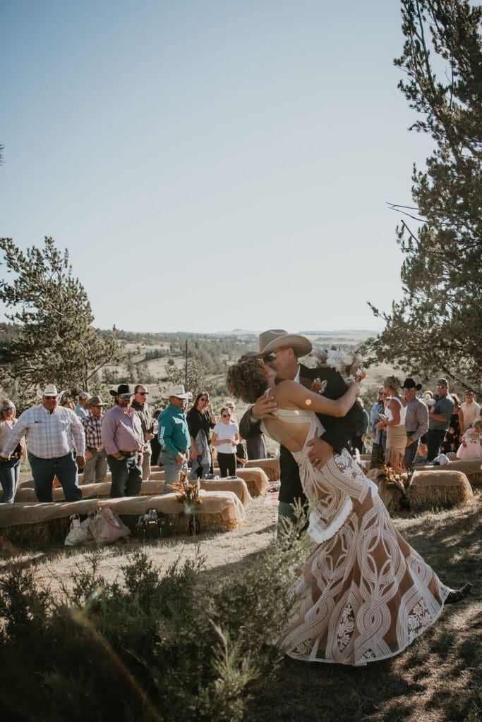 Bride in lace gown and groom in cowboy hat during rustic ranch wedding in Eastern Montana.