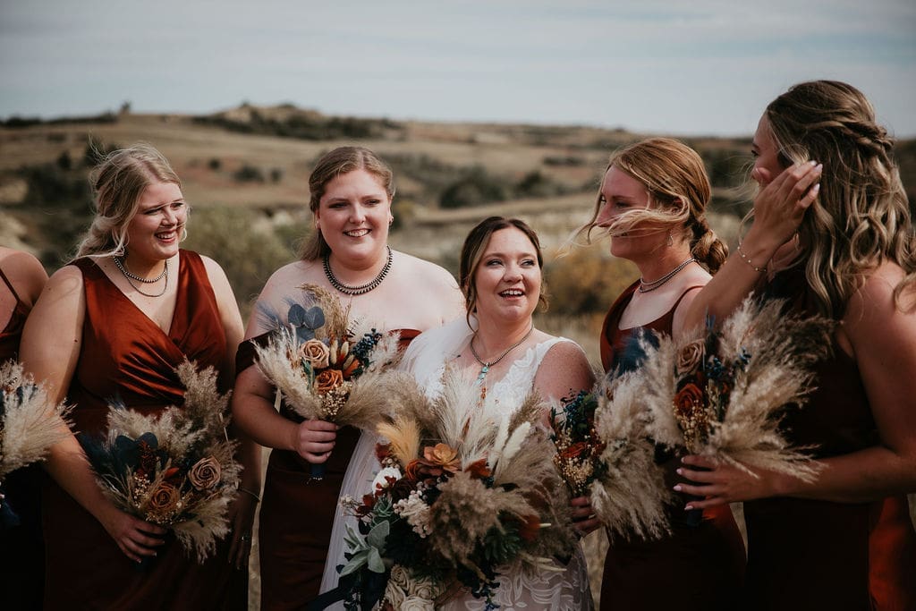 Bride laughing with bridesmaids holding rustic bouquets at Buffalo Gap wedding near Belfield North Dakota