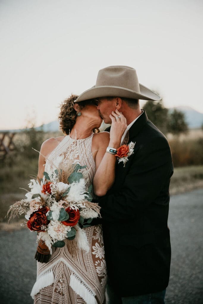 Couple sharing first kiss during outdoor ranch ceremony in Montana.