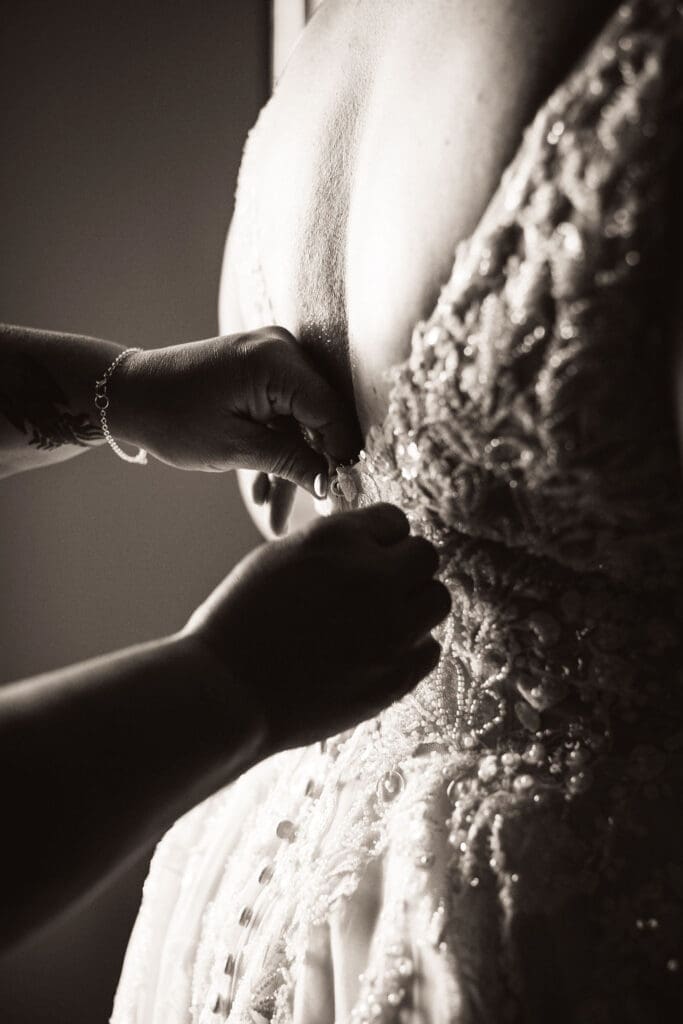 Bride getting buttoned into her dress by window light in Billings Montana wedding venue