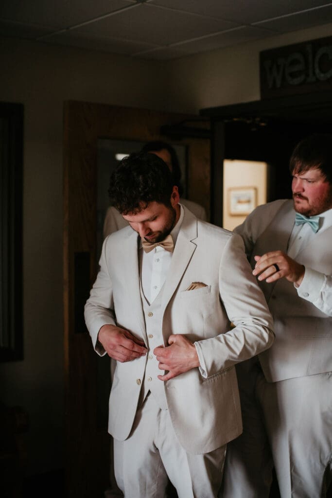 Groom adjusting his tie with soft light before ceremony in Billings