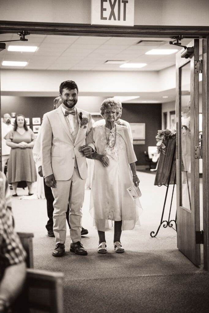 Groom posing outside chapel in cream suit before Billings wedding