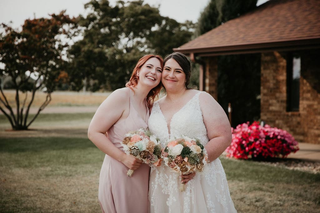 Bride and maid of honor laughing together before the reception