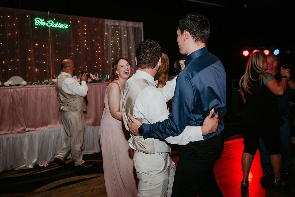 Friends laughing and dancing under reception lights in Billings