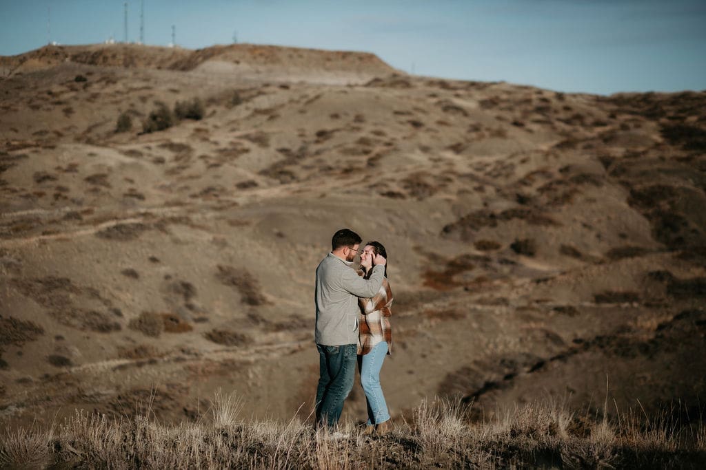 Candid photo of a couple walking hand in hand through tall grass at golden hour.