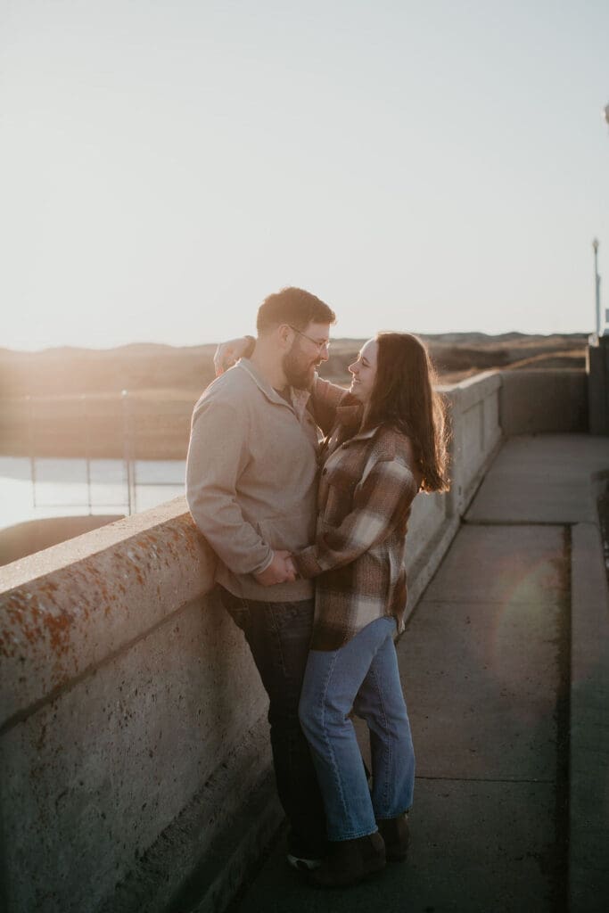 Couple leaning on each other with soft light and earthy tones of Montana hills.