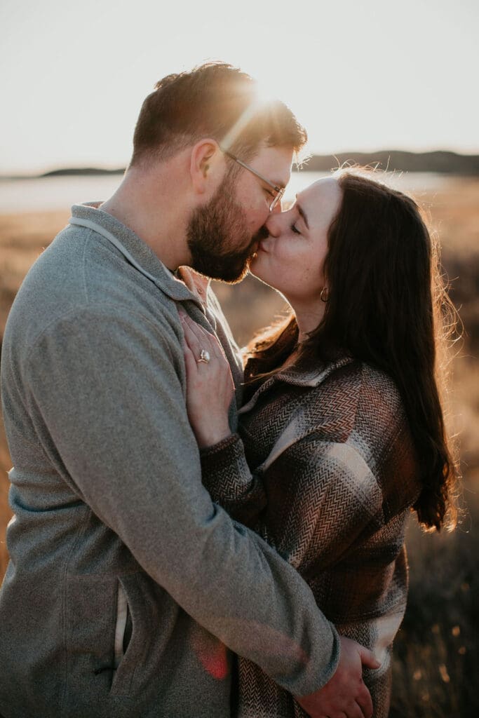Couple sharing a kiss at sunset in the hills, captured by Miles City Montana engagement photographer.