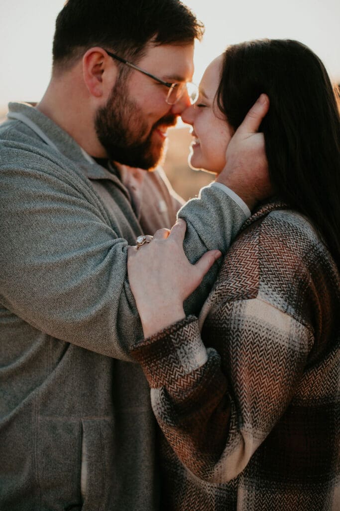 Tanner and Jaycie holding each other and smiling in golden Montana light during their engagement session.