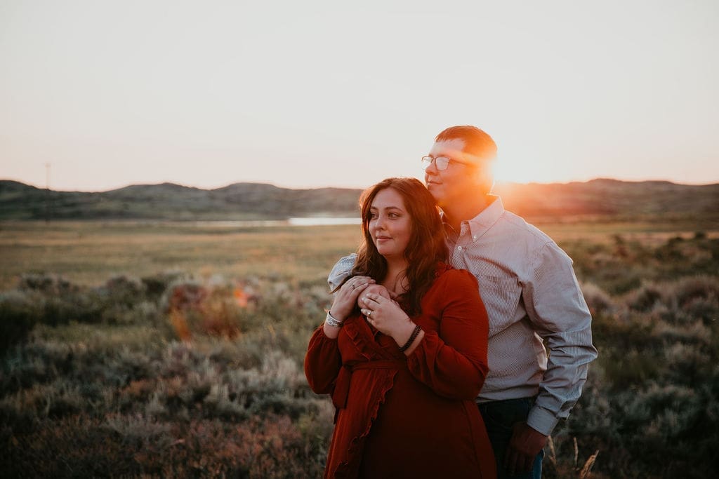Couple hugging by the water at Fort Peck after surprise engagement near Glasgow, MT